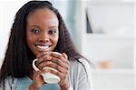 Close up of smiling woman sitting on sofa with a cup