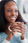 Close up of smiling woman on sofa having coffee