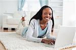 Smiling woman lying on the floor with her laptop