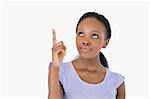 Close up of young woman pointing upwards on white background