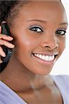 Close up of smiling woman talking on the mobile phone against a white background