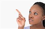 Close up of young woman pointing at something next to her on a white background