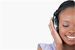 Close up of smiling young woman enjoying music on white background