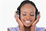 Close up of smiling young woman listening to music with headphones on white background