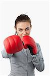 Businesswoman with boxing gloves slamming against a white background