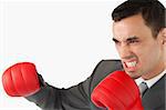 Side view of aggressive businessman with boxing gloves against a white background