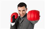 Businessman with boxing gloves on beating against a white background