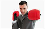 Close up of boxing glove being used by businessman against a white background