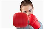 Close up of businesswoman striking with boxing gloves against a white background