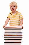 Portrait of a young boy standing behind a pile of books