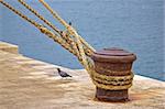 Rusty mooring bollard with ship ropes on Zadar docks