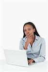 Thoughtful businesswoman using a laptop against a white background