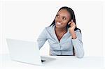 Smiling businesswoman making a phone call while using a laptop against a white background