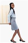 Portrait of a young businesswoman pushing a panel with her back against a white background