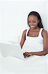 Portrait of a woman using a laptop before sleeping in her bedroom