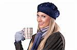 pretty blonde wearing warm winter clothes in grey and blue holding a hot cup of tea and smiling