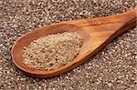 a wooden spoon of  organic ground chia seeds against the whole seeds background