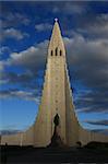 Dramatic clouds in the background of the famous church of Hallgrimur, also known as Hallgrimskirkja, in Reykjavik city in Iceland. Soft evening sunlight coming through the clouds to light up the church.