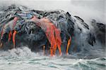 Red hot lava from Kilauea Volcano on the Big Island of Hawaii flows through lava tubes and pours like rivers into the ocean, bringing up clouds of steam and toxic gas, creating acres of lava rock and adding new land to the island.