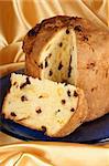 Panettone the italian Christmas fruit cake served on a blue glass plate over a yellow fabric background. Selective focus.