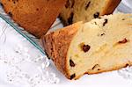 Panettone the italian Christmas fruit cake served on a transparent glass plate with some glass ornaments. Selective focus.