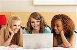 Group Of Three Teenage Girls Using Laptop In Bedroom
