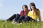 Twin Teenage Girls Sitting In Summer Meadow