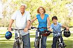 Grandparents And Grandson On Cycle Ride In Park