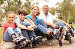 Grandparents And Grandchildren Putting On In Line Skates In Park