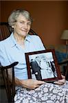 Senior Woman At Home Looking At Old Wedding Photo