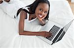 Woman lying on her belly using a notebook in her bedroom