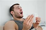 Sick man sneezing in his bedroom