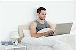 Calm man using a laptop in his bedroom