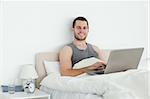 Serene man using a laptop in his bedroom