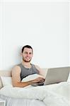 Portrait of a serene man using a laptop in his bedroom