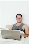 Portrait of a man using a notebook in his bedroom