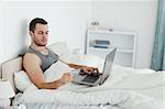 Young man purchasing online in his bedroom