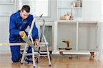 Handyman cutting a wooden board in a kitchen