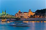 Budapest night view. Long exposure with boat silhouette on river. Hungarian landmarks, Freedom Bridge and Gellert Hotel Palace.