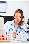 Doctor woman sitting in office and making phone call