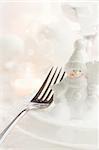 Christmas table setting. Fork and knife in elegant holiday setting with snow and white ornaments