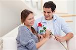 Man offering a rose to his fiance in their living room