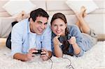 In love couple playing video games while lying on a carpet