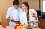 In love couple using a tablet computer to cook in their kitchen