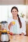 Portrait of a young woman drinking fresh fruits juice in her kitchen
