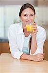 Portrait of a smiling woman drinking juice in her kitchen