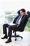 Portrait of a relaxed businessman sitting on an armchair working with a laptop in his office