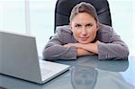 Businesswoman leaning on her desk while looking at the camera