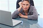 Serious businesswoman leaning on her desk