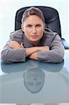 Portrait of a young businesswoman leaning on her desk while looking at the camera